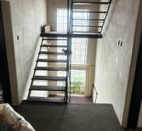 Interior of a staircase in a family house with a metal railing and a window facing the street.