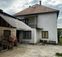 A family house in Bzovík with an unplastered facade and an extension made of corrugated sheet metal.