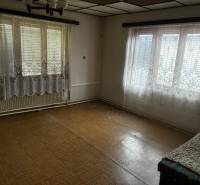 The interior of a family house with two windows, curtains, and parquet flooring.