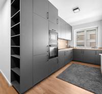 A kitchen in a 3-room apartment with gray cabinets and a wooden floor.
