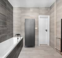 A bathroom with a bathtub, gray tiles, and black accessories in a 3-room apartment.