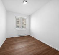 An empty room with a wooden floor and a window in a three-room apartment.