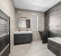 Spacious bathroom in a 3-room apartment with gray tiles, double sink, and bathtub.