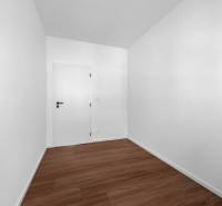 An empty room with white walls and wooden flooring in a 3-room apartment.