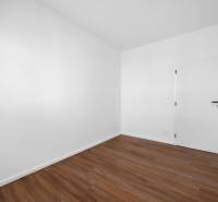 An empty room with wooden flooring and white walls in a 3-room apartment.
