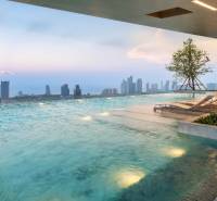 A pool with loungers and a view of the Pattaya city skyline from the apartment construction.