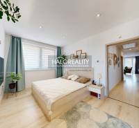 A bedroom in a 3-room apartment with a bed, television, and plants, bright interior.