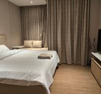 Bedroom in a studio apartment with a double bed, sofa, and curtains.