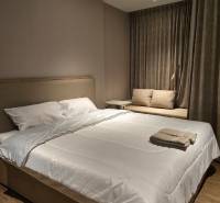 Bedroom in a one-room apartment with a double bed and a brown carpet.