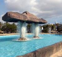 A fountain with an unusual stone structure and water streams in a beautiful setting.