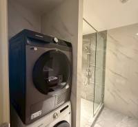 Functional bathroom with a washing machine and dryer in a 3-room apartment with a modern shower.