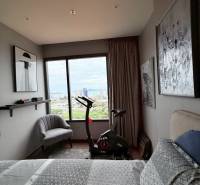 Bedroom in a 3-room apartment with a stationary bike and a view of the city.
