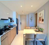 Kitchen and dining area in a 3-room apartment with wooden and white cabinets.
