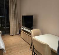 Interior of a 1-room apartment with a table, chairs, television, and curtains. Without mentioning the city.