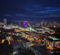 A night view of the city of Pattaya with illuminated buildings and silhouettes on the horizon.