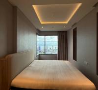 A bedroom in a three-room apartment with a large window and a view of the city.