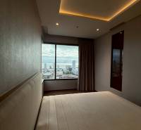 A bedroom in a 3-room apartment with a view of the city through a large window.
