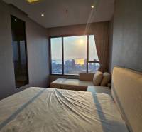 A bedroom in a 3-room apartment with a view of the sunset over the city.