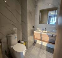 A bathroom with marble tiles and a toilet in a 3-room apartment.