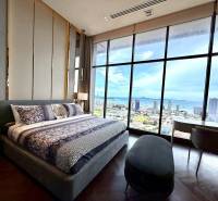The bedroom in the 4-room apartment with a large window offers a view of the city and the coast.