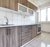 A kitchen in a 2-room apartment with wooden cabinets and white tiles, bright space.