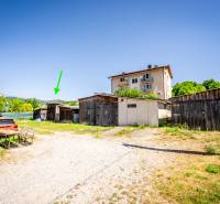 A yard with several wooden buildings and a parked car in Púchov, near a 2-room apartment.