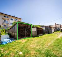 A yard with wooden cottages and an apartment building in Púchov.