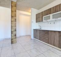 A kitchen in a 2-room apartment with wooden paneling and tiled flooring.