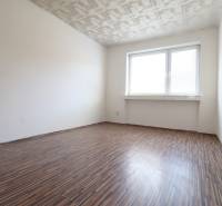 An empty room with a patterned floor and a large window in a 2-room apartment.
