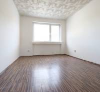 An empty room with a wooden floor and a white ceiling in a 2-room apartment.