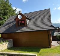 A cottage in Nová Bystrica with a wooden facade and a satellite, surrounded by nature.