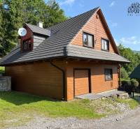 A cottage in Nová Bystrica surrounded by greenery with a satellite dish on the roof.