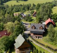 A cottage in Nová Bystrica surrounded by green hills and forests, a peaceful mountain landscape.