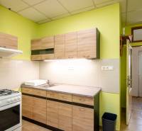 A kitchen with a gas stove, wooden cabinets, and a light green wall in a 2-room apartment.