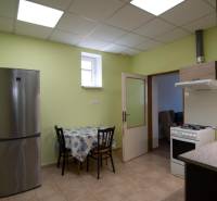 A kitchen with a table, refrigerator, and stove in a 2-room apartment, light green walls.