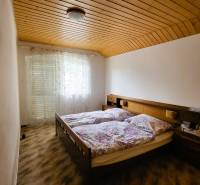 A bedroom in a family house with two beds, a wooden ceiling, and a curtain.