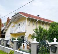 A family house in Dunaszige with a red roof, a balcony, and a well-maintained garden.