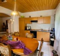 Dining room and kitchen in a family house with a wooden ceiling and decorative lighting.