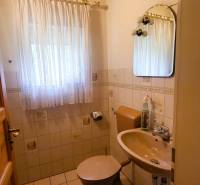 A bathroom in a family house with tiles, a curtain, and a mirror.