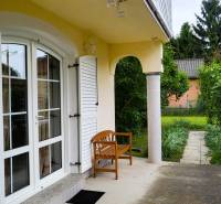 A family house in Dunaszigeţ with a terrace and a bench surrounded by a garden.