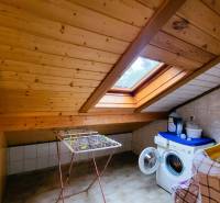 Attic laundry room with a wooden ceiling and a skylight, washing machine, clothes drying rack.