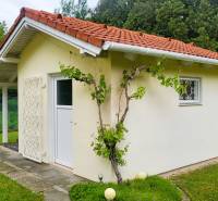 A family house in Dunaszeg with a red roof, grapevines, and a lawn in the garden.