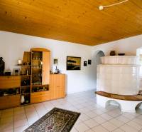 Living room in a family house with a white tiled stove and a wooden ceiling.