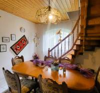 A dining room in a family house with a wooden ceiling, stairs, and decorative lighting.
