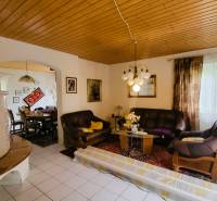 Living room in a family house with a tiled stove, sofa, and dining table.