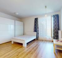 A bright room with a bed, a wardrobe, and a wooden floor in a studio apartment.