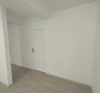 White walls and doors in commercial spaces with wooden flooring.