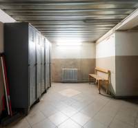 Warehouses and halls with metal lockers, a bench, and cleaning supplies in the corner.