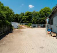Paved area at the warehouse hall on Kasárenská Street in Trenčín surrounded by greenery.