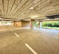 Garages with lights, parking spaces, and columns, Senica, Sadová, view of greenery.